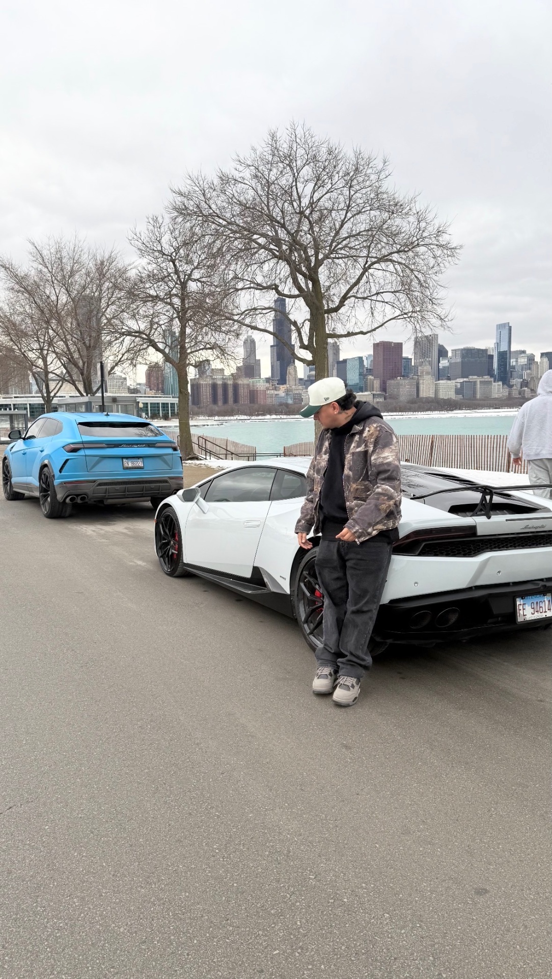 Nate Fernandez, founder of NF Industries, with a white Lamborghini Huracán and blue Lamborghini Urus on the Chicago lakefront